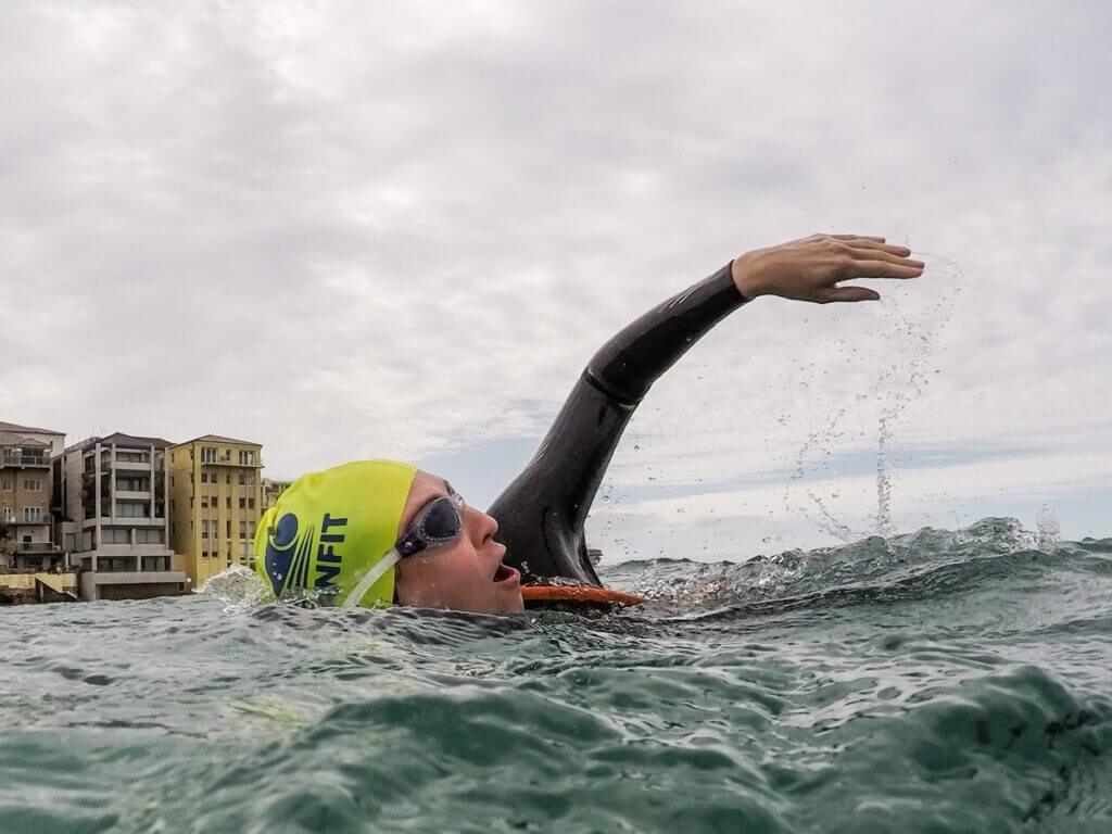 female ocean swimming with a fluro swim cap