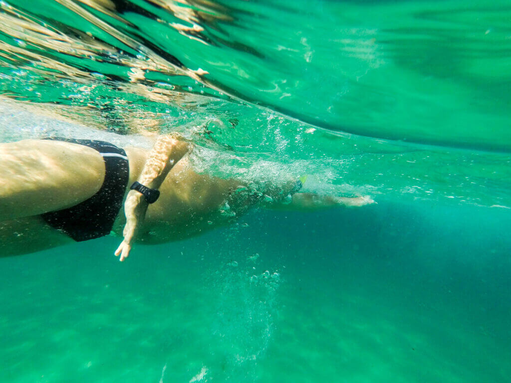An ocean swimmer wearing a sports watch while swimming in the ocean